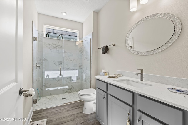 bathroom with hardwood / wood-style flooring, vanity, an enclosed shower, a textured ceiling, and toilet