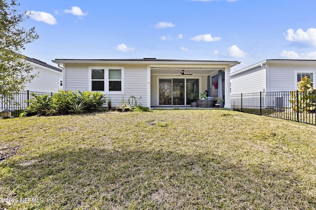 rear view of property featuring ceiling fan and a yard