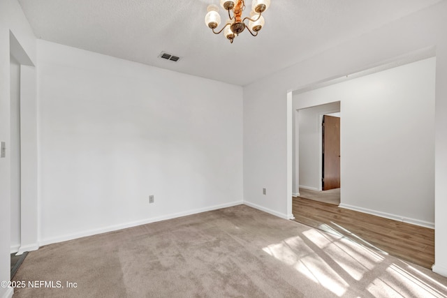 unfurnished room featuring light colored carpet, an inviting chandelier, and a textured ceiling