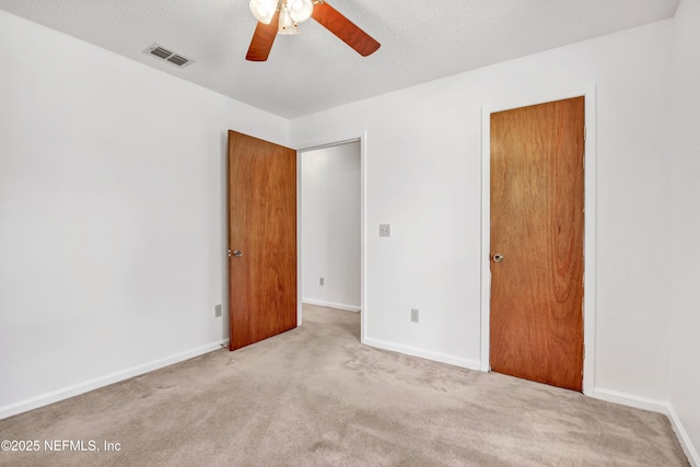 unfurnished room with ceiling fan, light colored carpet, and a textured ceiling