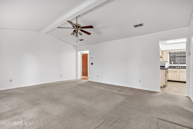 empty room with ceiling fan, sink, lofted ceiling with beams, and light carpet