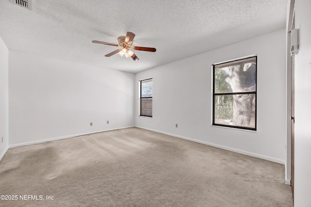 empty room featuring a textured ceiling, ceiling fan, a healthy amount of sunlight, and light carpet