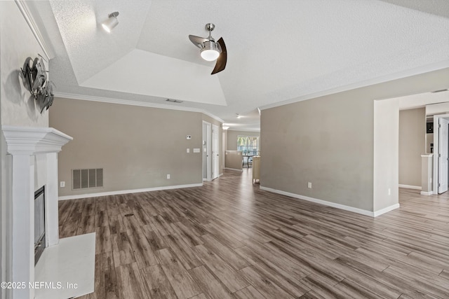 unfurnished living room with hardwood / wood-style floors, ceiling fan, a raised ceiling, a fireplace, and ornamental molding