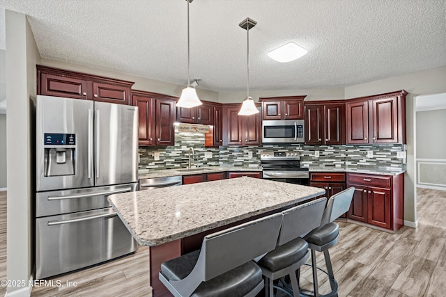 kitchen with pendant lighting, a center island, sink, a kitchen breakfast bar, and stainless steel appliances