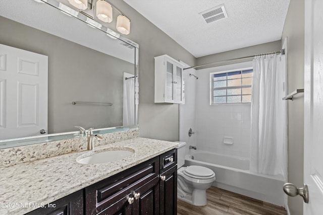 full bathroom featuring hardwood / wood-style floors, a textured ceiling, vanity, shower / tub combo, and toilet