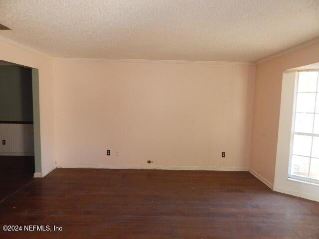 empty room with dark hardwood / wood-style flooring, plenty of natural light, and a textured ceiling