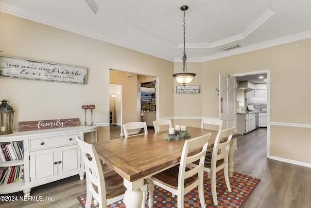 dining space featuring dark wood-type flooring, a tray ceiling, and ornamental molding