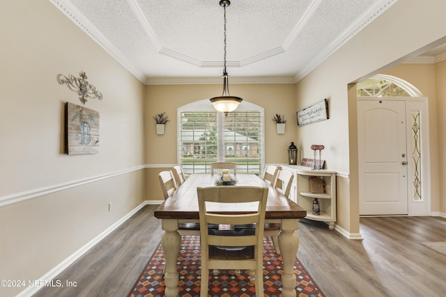 dining room featuring a textured ceiling, crown molding, hardwood / wood-style floors, and a tray ceiling