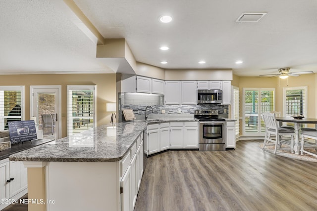 kitchen with appliances with stainless steel finishes, white cabinetry, decorative backsplash, sink, and light stone counters