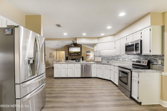 kitchen featuring white cabinets, backsplash, appliances with stainless steel finishes, and vaulted ceiling