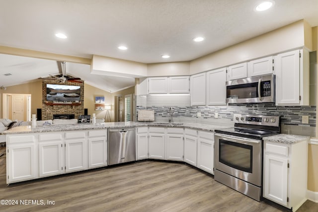 kitchen with vaulted ceiling with beams, kitchen peninsula, appliances with stainless steel finishes, and white cabinetry