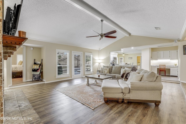 living room featuring a textured ceiling, hardwood / wood-style floors, plenty of natural light, and lofted ceiling with beams