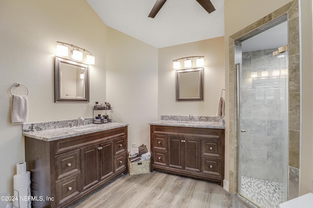 bathroom featuring ceiling fan, vanity, wood-type flooring, a shower with shower door, and a textured ceiling