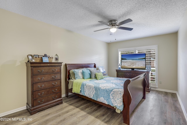 bedroom with ceiling fan, a textured ceiling, and light hardwood / wood-style flooring