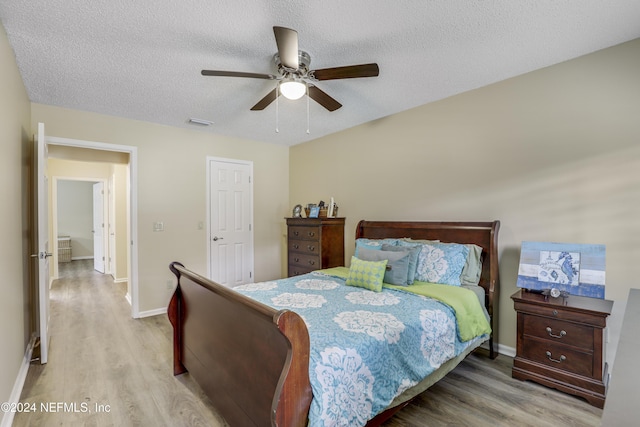 bedroom featuring a textured ceiling, ceiling fan, and light hardwood / wood-style floors