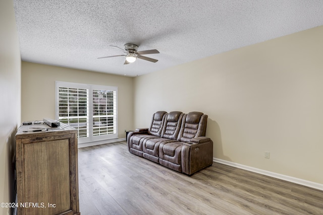 living room featuring light hardwood / wood-style floors, a textured ceiling, and ceiling fan