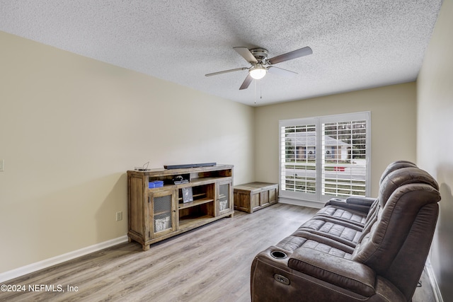 living room with a textured ceiling, ceiling fan, and light hardwood / wood-style flooring