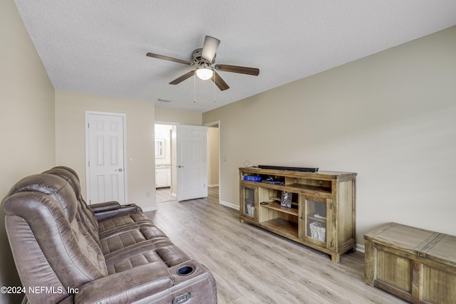 living room featuring ceiling fan, a textured ceiling, and light hardwood / wood-style flooring