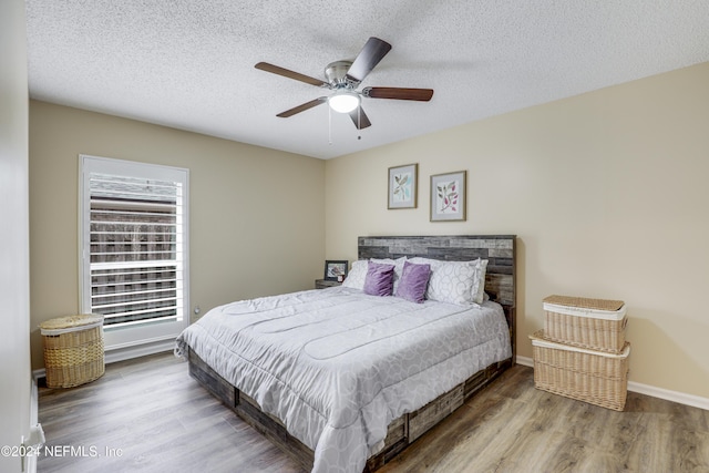 bedroom with ceiling fan, a textured ceiling, and hardwood / wood-style floors