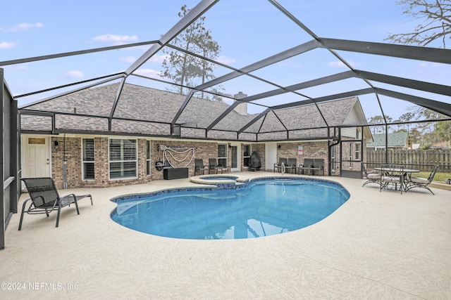 view of swimming pool with glass enclosure, an in ground hot tub, and a patio