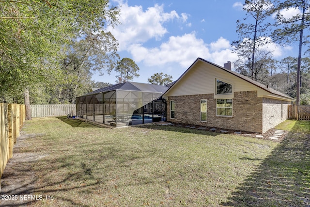 rear view of house with glass enclosure, a pool, and a lawn