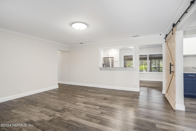 unfurnished living room with a barn door, dark wood-type flooring, and ornamental molding