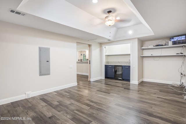 unfurnished living room with dark hardwood / wood-style floors, ceiling fan, a raised ceiling, and electric panel