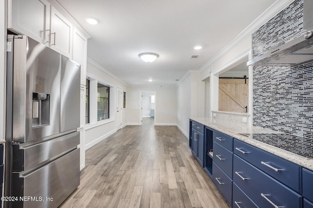 kitchen with white cabinetry, light stone countertops, wall chimney range hood, a barn door, and stainless steel fridge with ice dispenser