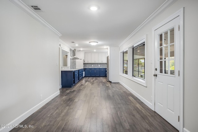 interior space featuring blue cabinetry, white cabinetry, wall chimney exhaust hood, stainless steel fridge, and decorative backsplash