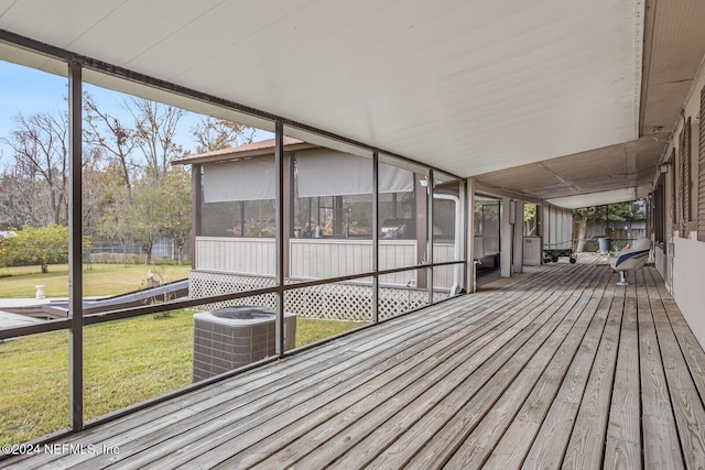 deck featuring central air condition unit, a sunroom, and a lawn