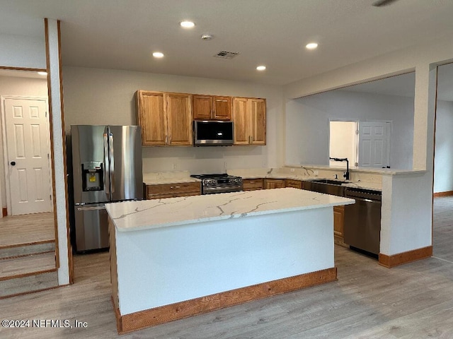 kitchen with a center island, sink, appliances with stainless steel finishes, and light hardwood / wood-style flooring