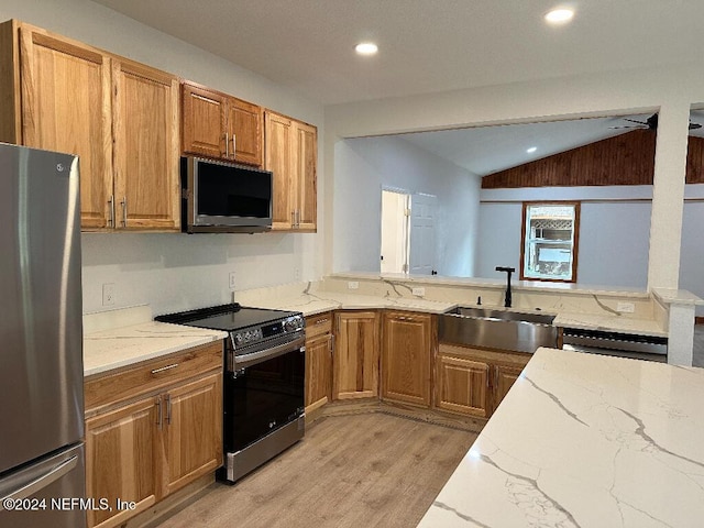 kitchen with sink, light hardwood / wood-style flooring, vaulted ceiling, appliances with stainless steel finishes, and light stone counters