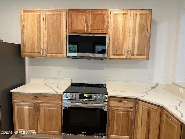 kitchen with appliances with stainless steel finishes and light stone counters