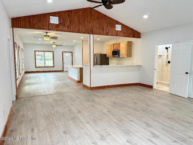 unfurnished living room featuring wooden walls, ceiling fan, light wood-type flooring, and high vaulted ceiling