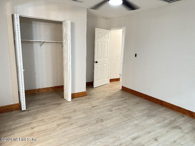 unfurnished bedroom featuring ceiling fan, a closet, and light hardwood / wood-style flooring