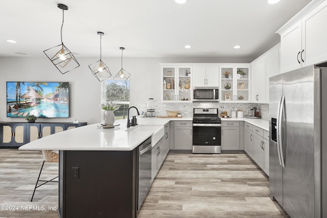 kitchen with pendant lighting, gray cabinetry, a kitchen breakfast bar, sink, and appliances with stainless steel finishes