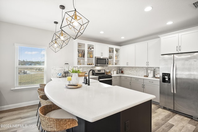 kitchen with appliances with stainless steel finishes, decorative light fixtures, light hardwood / wood-style floors, and sink