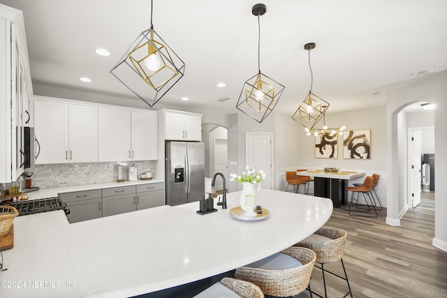 kitchen featuring light hardwood / wood-style floors, stainless steel fridge with ice dispenser, gray cabinets, white cabinetry, and hanging light fixtures