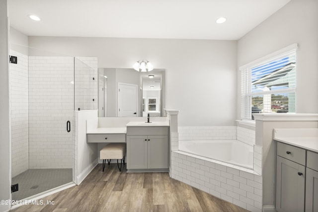 bathroom with hardwood / wood-style floors, vanity, and shower with separate bathtub