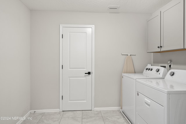 washroom featuring cabinets, independent washer and dryer, a textured ceiling, and light tile patterned floors