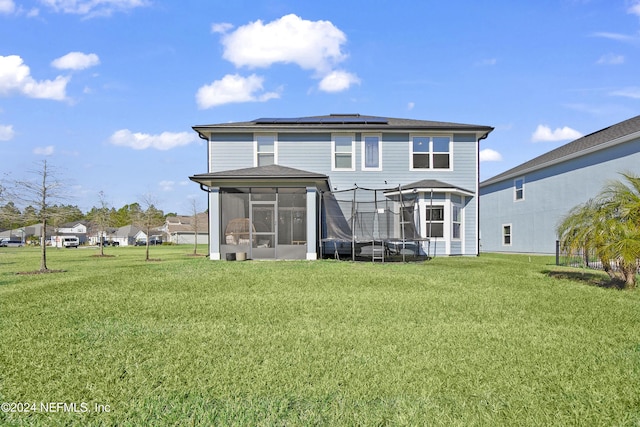 back of property with solar panels, a yard, and a sunroom