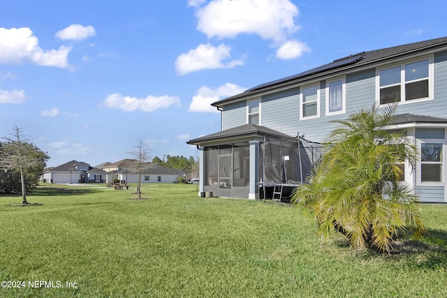 rear view of property with solar panels, a yard, and a sunroom