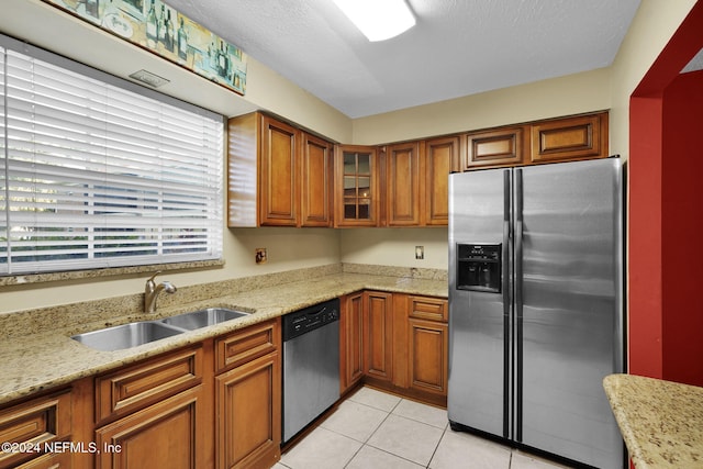 kitchen with light stone counters, sink, light tile patterned floors, and stainless steel appliances