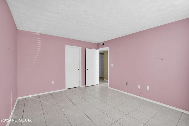 unfurnished room featuring light tile patterned floors and a textured ceiling