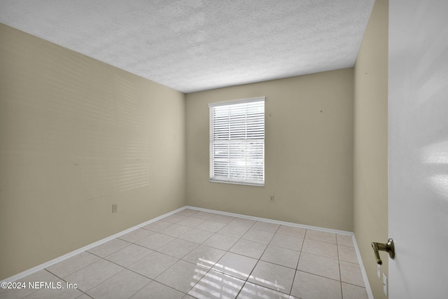 unfurnished room with light tile patterned floors and a textured ceiling