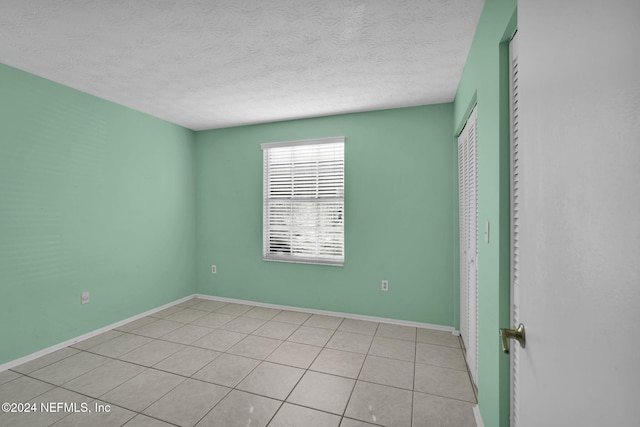 empty room with light tile patterned floors and a textured ceiling