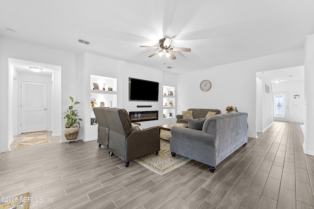 living room featuring ceiling fan and built in features