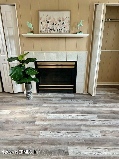 details featuring a tiled fireplace, wooden walls, and hardwood / wood-style floors