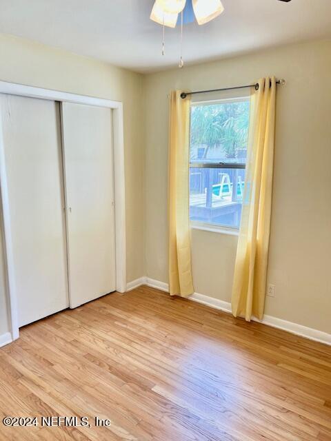 unfurnished bedroom featuring a closet, light hardwood / wood-style flooring, and ceiling fan