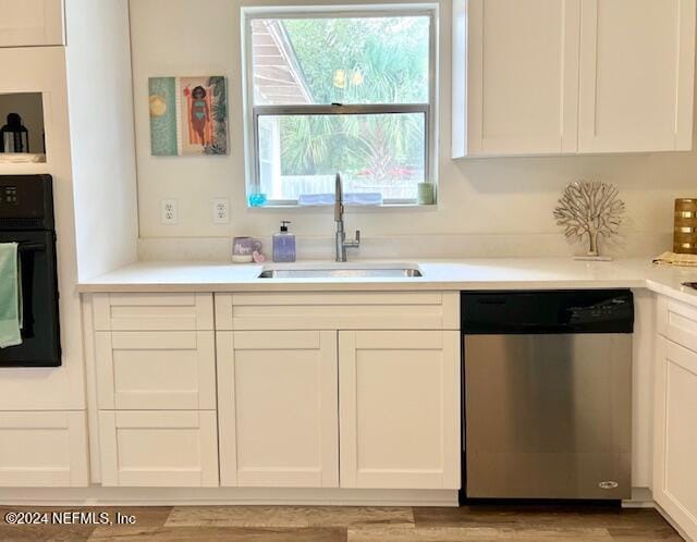 kitchen featuring white cabinets, black oven, stainless steel dishwasher, and sink